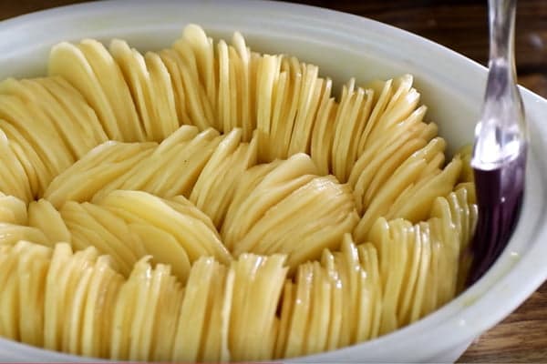 Нарезанный картофель в форме для выпечки