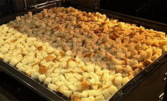 Пока мясо стоит в холодильнике, займитесь приготовлением панировочных сухарей. Возьмите батон и нарежьте его небольшими кубиками. Достаньте противень из духовки, застелите его пергаментной бумагой, постарайтесь равномерно разместить на нем кубики батона (духовка должна быть предварительно разогрета до 150 градусов). Готовьте кубики в течение 10 минут.