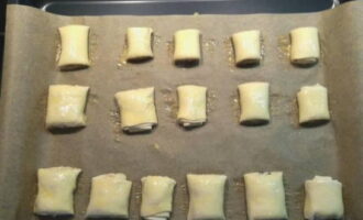 Аккуратно переложите кусочки на лист для выпечки, выстеленный пергаментной бумагой, и щедро смажьте оставшимся взбитым яйцом.